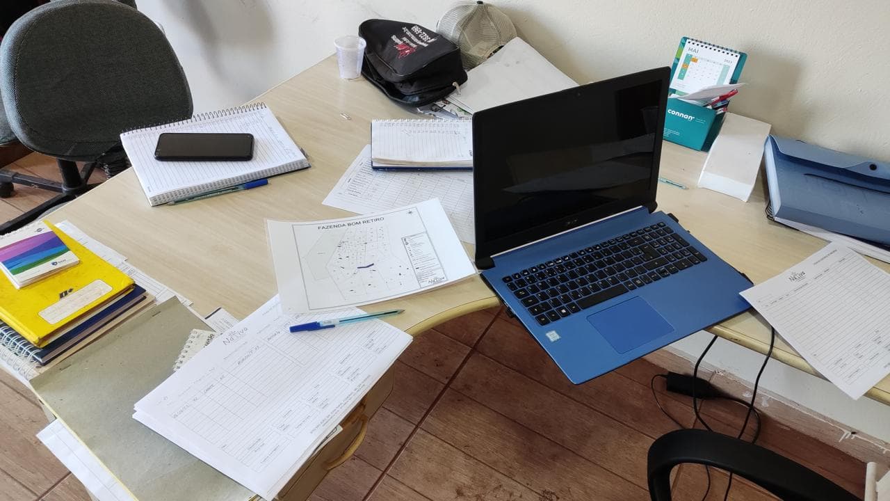 A farm office desk with a laptop, notebooks and a georeferenced property map used for business planning.